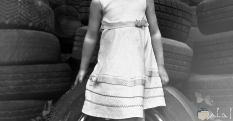 خلفية معبرة جميلة لفتاه صغيرة تجلس على عجل سيارة قديم.