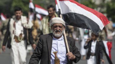 رجل عجوز يحمل العلم اليمني بفخر